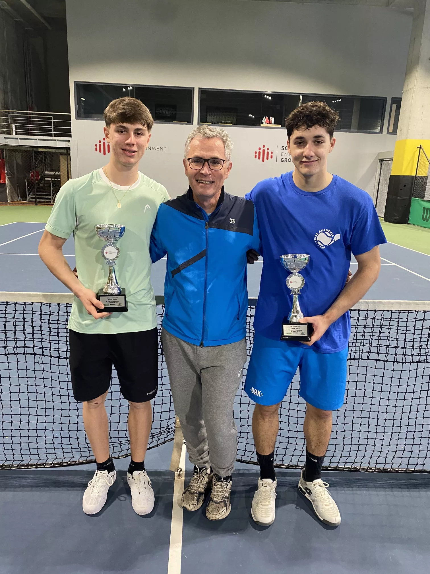 Frank Trötschkes mit zwei jungen Tennisspielern und ihren Turnierpokalen in der Tennishalle
